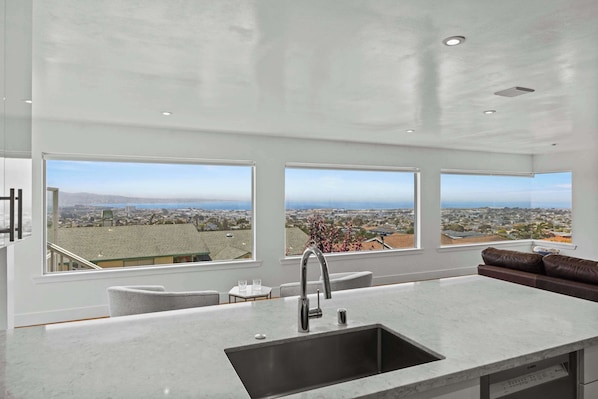 A modern kitchen with large windows, a sink, and a view of a cityscape.