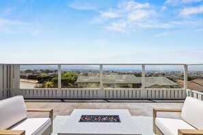 A balcony with a view of a residential area, a fire pit, and two white sofas. - New 3B 3BA Panoramic Ocean Views 30 Night Min (Seaside)