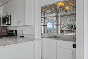 A modern kitchen with a built-in microwave, stove, and a glass display case with wine glasses.