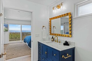 A bathroom with a large mirror, a sink with gold fixtures, and a view of a balcony.