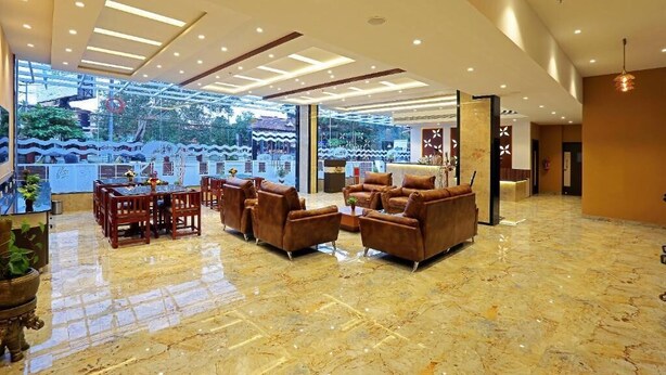 A spacious lobby with a high ceiling, marble flooring, and a seating area with sofas and chairs. - Renai Sreekrishna (Guruvayur)