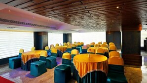 A conference room with multiple round tables and chairs, arranged in rows. - Renai Sreekrishna (Guruvayur)
