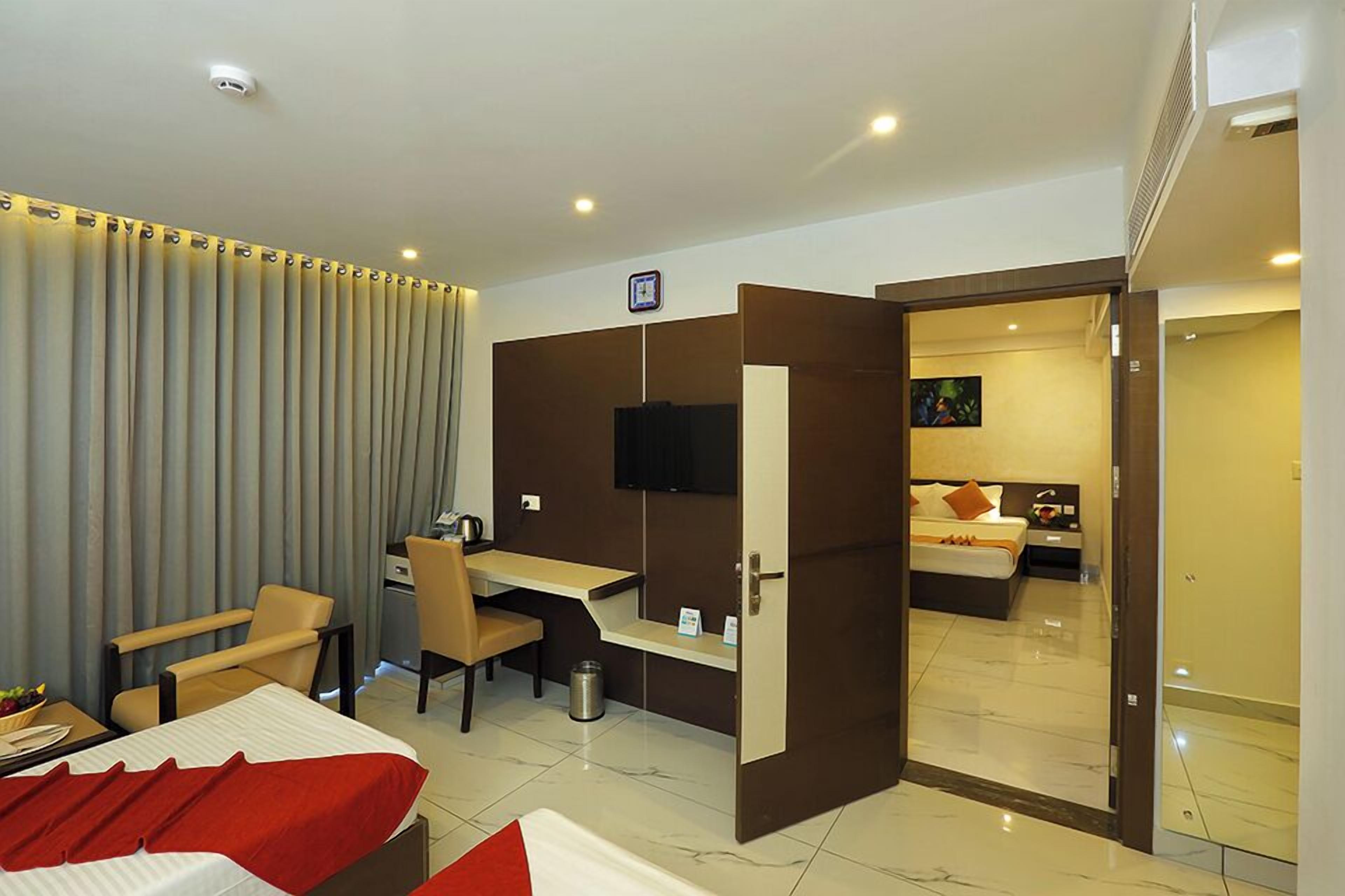 Habitación de hotel con cama, escritorio, silla y televisor.