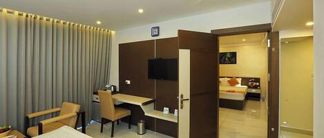 A hotel room with a bed, desk, chair, and a television.