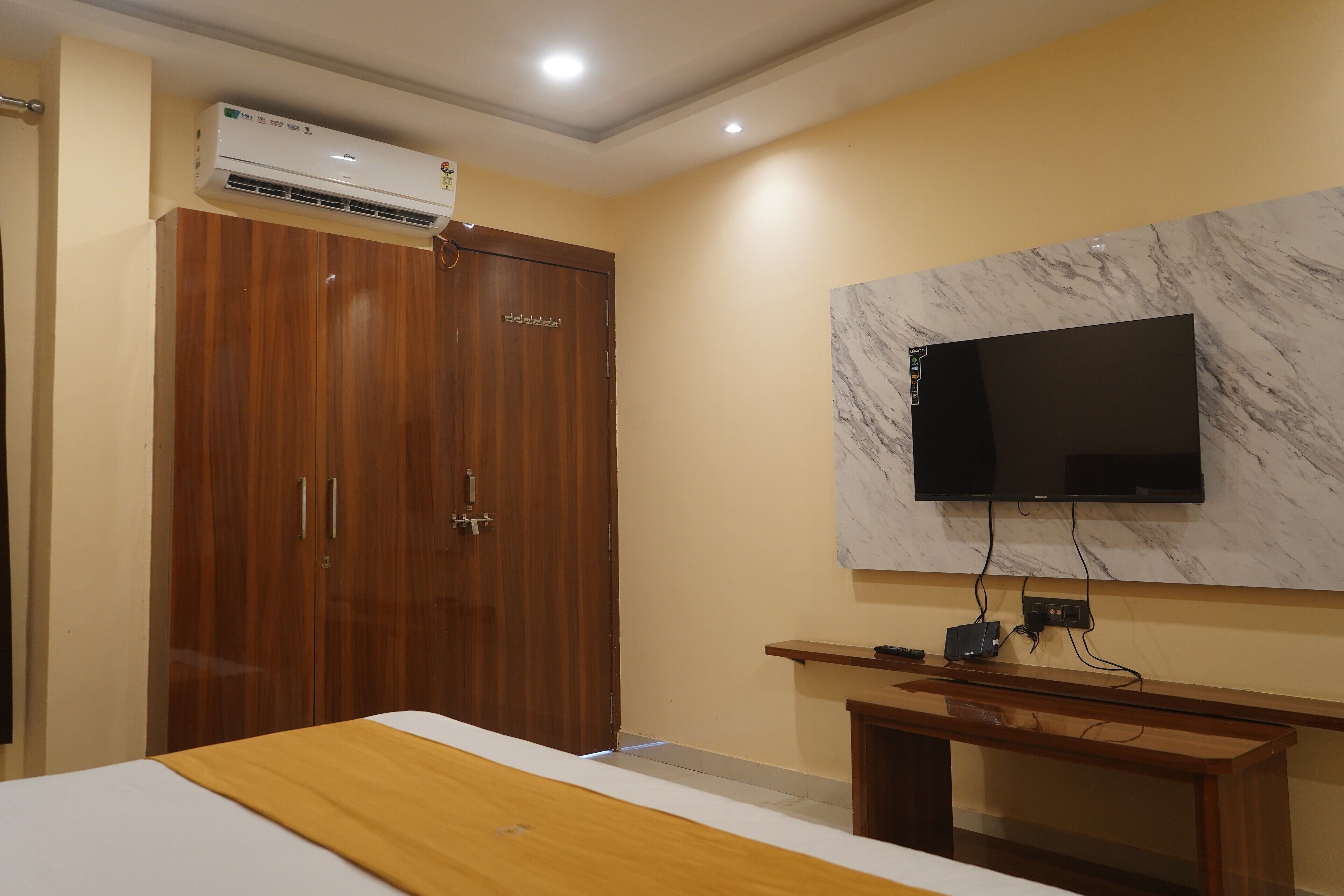 Habitación de hotel con cama, armario de madera, televisor montado en la pared y equipo de aire acondicionado.
