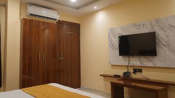 Habitación de hotel con cama, armario de madera, televisor montado en la pared y equipo de aire acondicionado.