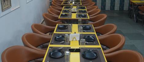 Una larga mesa de comedor con sillas marrones, dispuesta con platos, cubiertos y el logotipo de McDonald's.