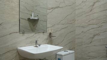 A bathroom with a marble wall, a sink, a toilet, and a mirror.