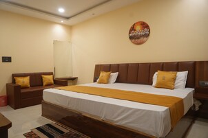 A hotel room with a large bed, a sofa, a small table, and a wall-mounted artwork.