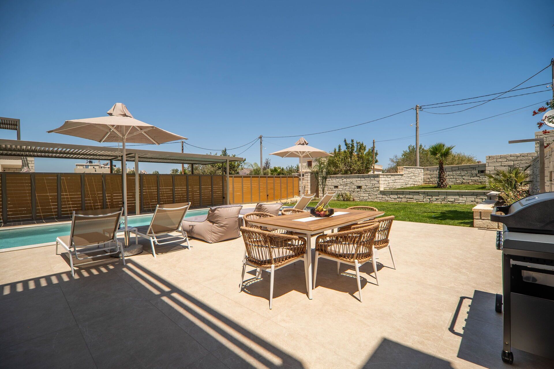 Une terrasse extérieure avec une piscine, des chaises longues, une table à manger et des parasols.