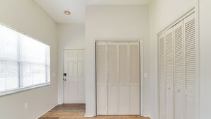 En hall med trägolv, vita väggar och en dörr med skjutdörrar som döljer ett inbyggt skåp.