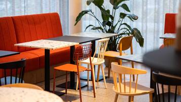 A modern dining area with a red sofa, wooden chairs, and a table with a menu.