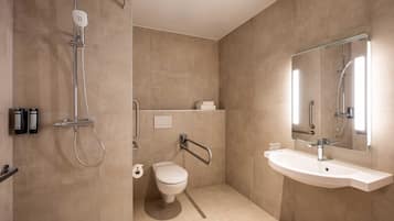 A modern bathroom with a shower, toilet, and sink, featuring a glass shower enclosure and a large mirror.