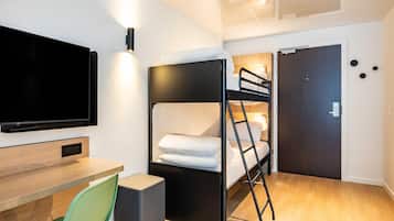 A bunk bed room with a TV, desk, and chair.