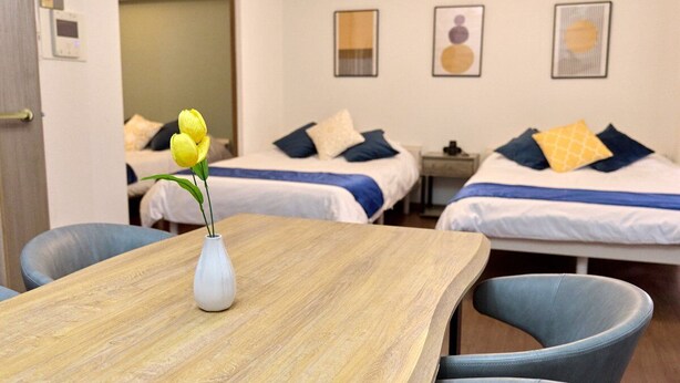 Ein Hotelzimmer mit zwei Betten, einem Holztisch mit Blumenvase und einem Sessel.