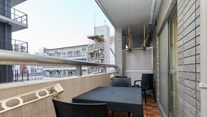 Ein Balkon mit Tisch, Stühlen, einer Brüstung und Blick auf Gebäude.