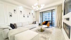 A modern living room with a sectional sofa, a round coffee table, and a bright chandelier. - Alba Gardens B1102 (Nairobi)