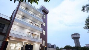 A multi-story building with balconies and a water tower in the background. - Anandam Grand (Greater Noida)