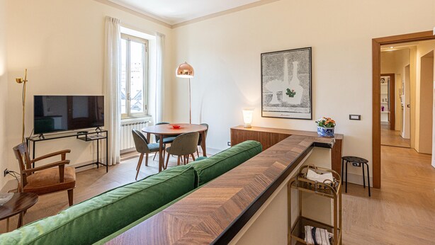 A modern living room with a sofa, TV, dining table, and chairs.