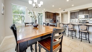 A spacious kitchen with dark wooden cabinets, a central island with seating, and a chandelier. - King Bed • Keyless Entry • Workspace • Fast WiFi • Chef's Kitchen • Central Loc. (Visalia)