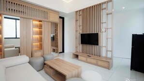 A modern living room with a flat-screen TV, built-in wooden shelving, and a sofa. - Kamaimo Villa (Munggu)