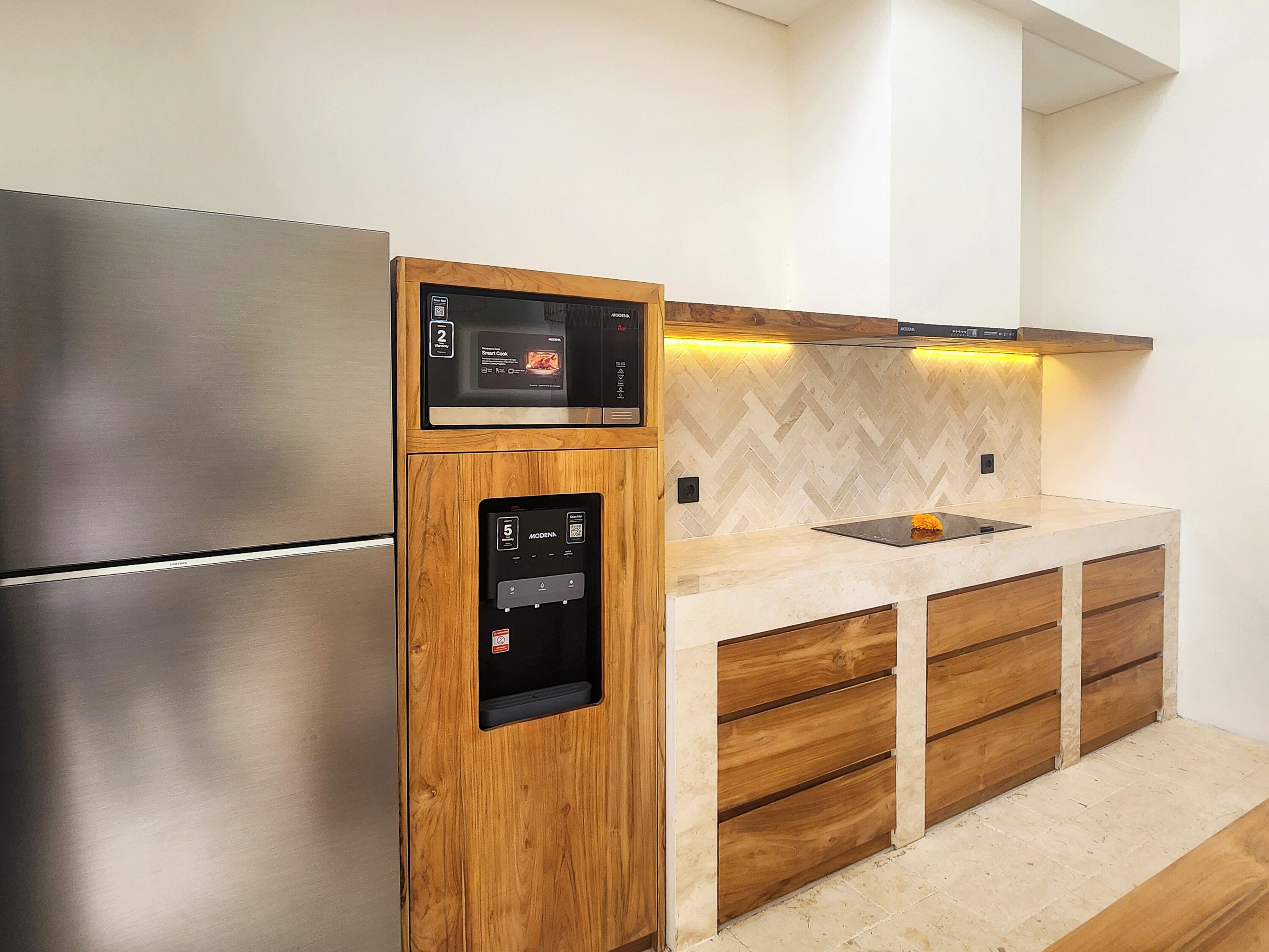 Une cuisine moderne dotée d’un réfrigérateur en acier inoxydable, d’un meuble en bois avec un distributeur d’eau intégré et d’un dosseret décoré d’un motif en chevrons.