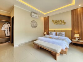 Una habitación de hotel moderna con una cama grande, mesitas de noche, un banco, un armario y un adorno en la pared.