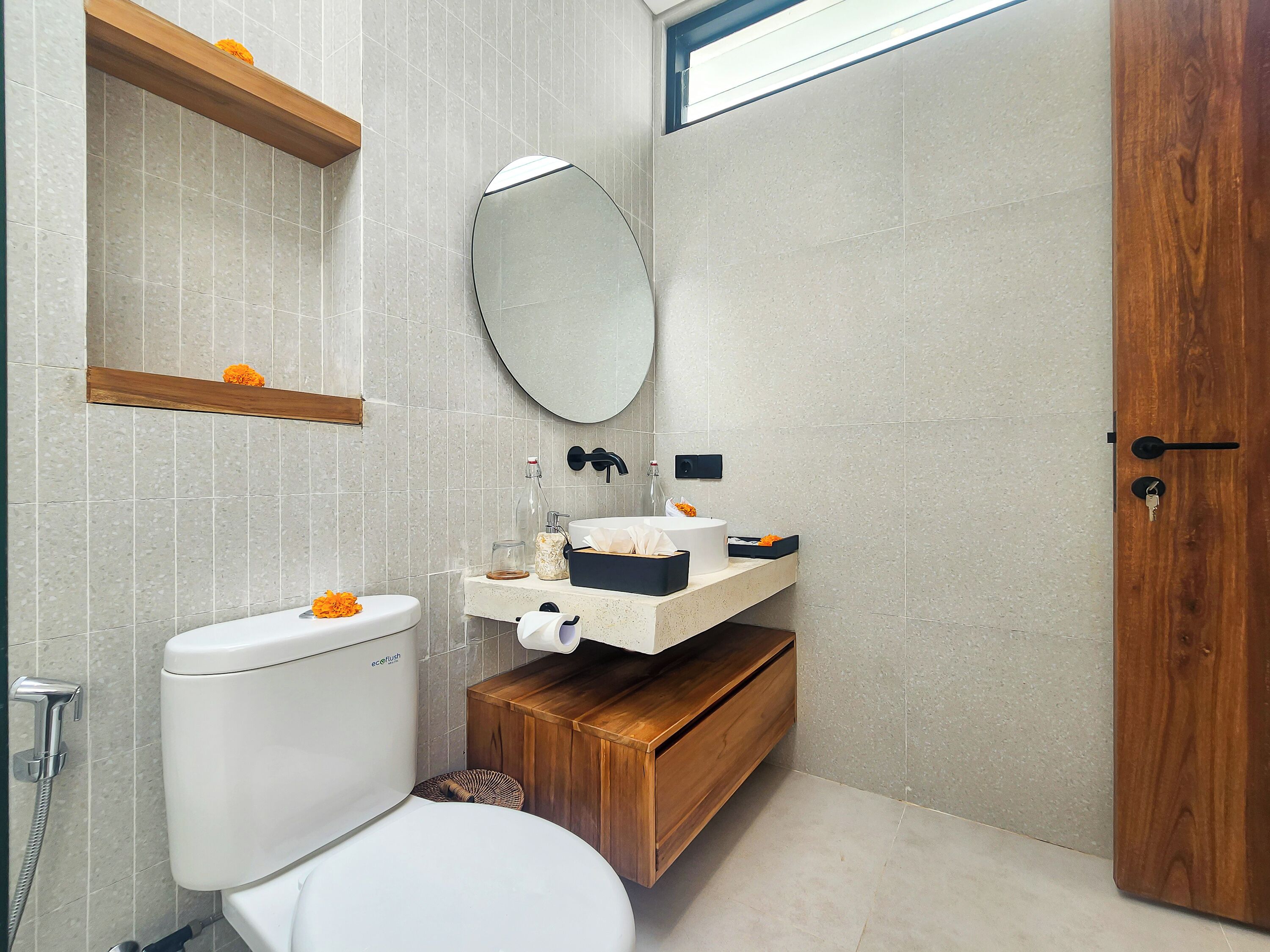 A bathroom with a toilet, sink, mirror, and wooden vanity.