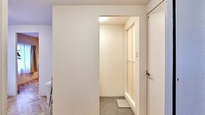 A hallway with a wooden floor, a white door, and a small step leading to another room. - XS41 XROSS STAY Juso1 (大阪市淀川区十三東)