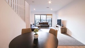 Un salon moderne avec une table à manger ronde, un canapé et un téléviseur.