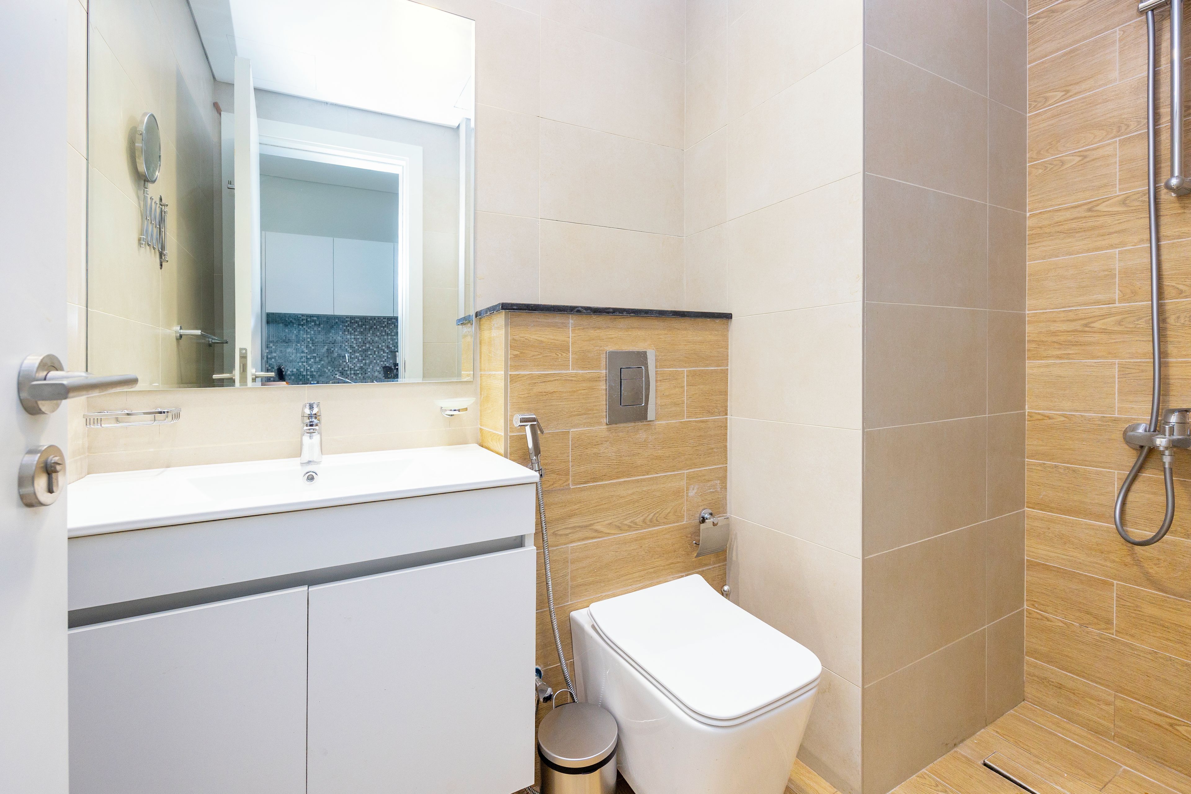 Un baño moderno con un lavabo, espejo y retrete blancos.