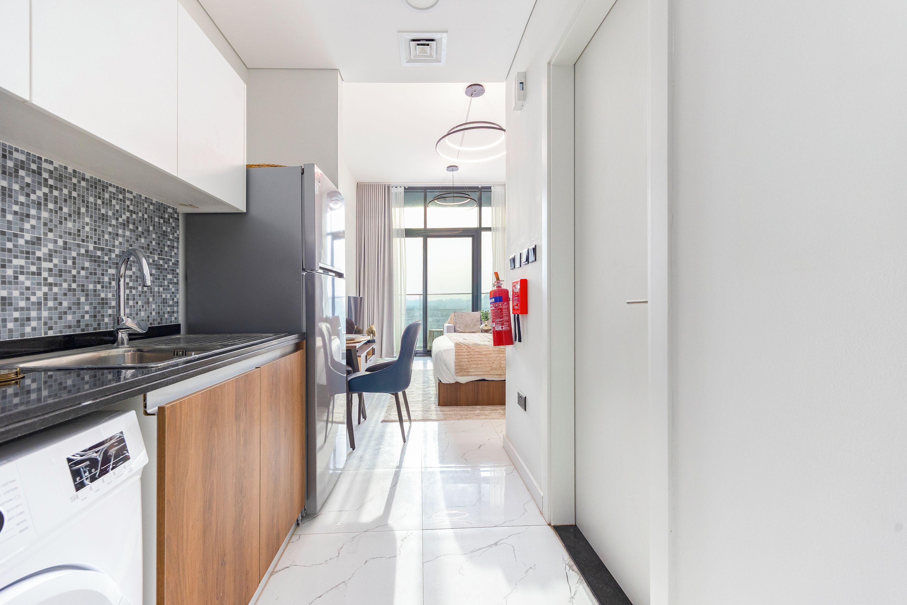 A modern kitchen with a tiled backsplash, a built-in oven, and a stainless steel range hood.