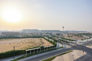 A modern urban landscape with wide roads, pedestrian pathways, and high-rise buildings in the background. - Bloomfields Studio in The Gate-Masdar (Abu Dhabi)