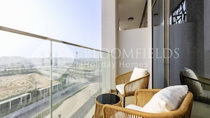 A balcony with wicker furniture and a view of a cityscape. - Bloomfields Comfort Stu The Gate  (Abu Dhabi)