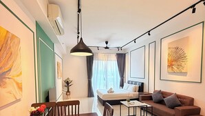 Une chambre d’hôtel moderne comprenant un coin repas, un canapé, un lit et des œuvres d’art accrochées aux murs.