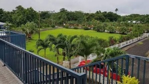 Une vue depuis un balcon donnant sur un jardin bien entretenu, avec des palmiers et une pelouse.