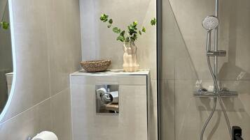 Tweepersoonskamer | Badkamer | Een douche, een haardroger, handdoeken, toiletpapier