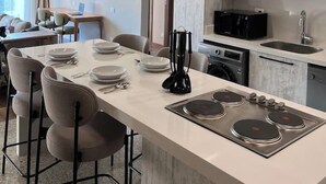 A modern kitchen with a central island, built-in appliances, and a dining area with chairs and a table. - Kennah Meraviglia | Lake View Residence, New Cairo (New Cairo)