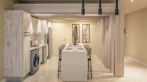 A modern kitchen with a built-in washing machine, a dining area with a long table, and pendant lighting. - Kennah Meraviglia | Lake View Residence, New Cairo (New Cairo)