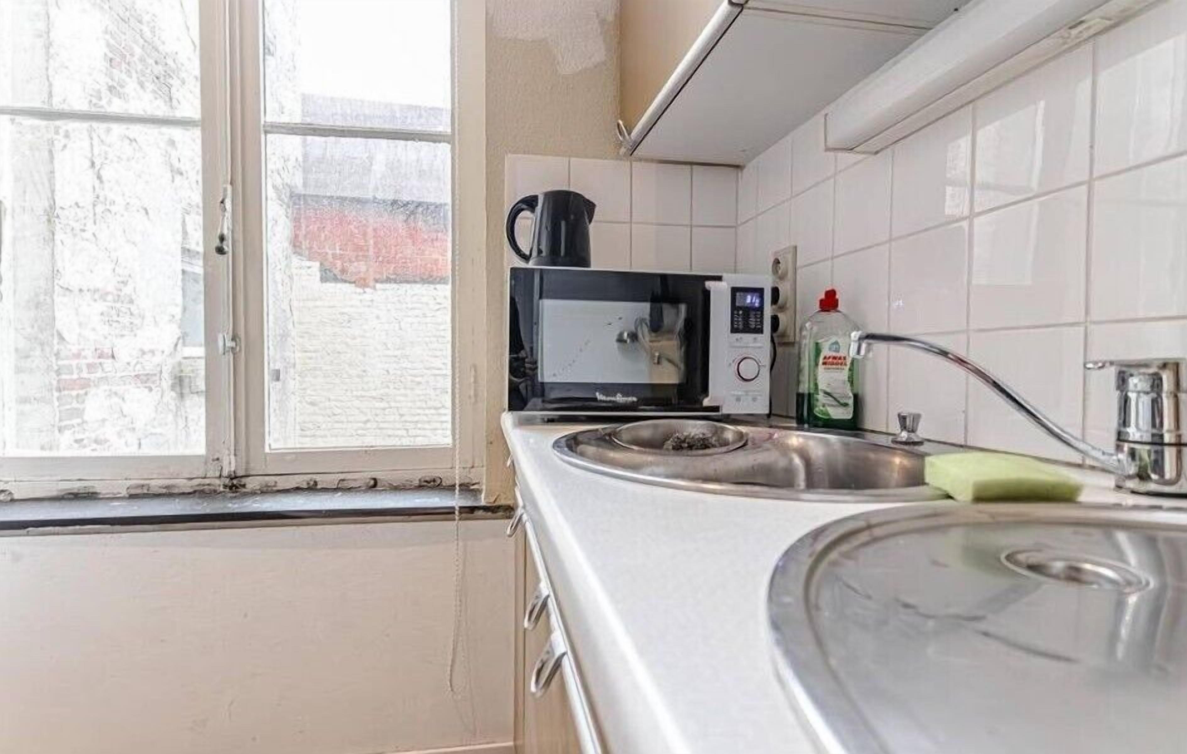 A kitchen with a microwave, sink, and window.