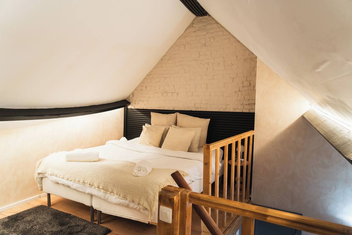 A bedroom with a bed, wooden headboard, and a brick wall.