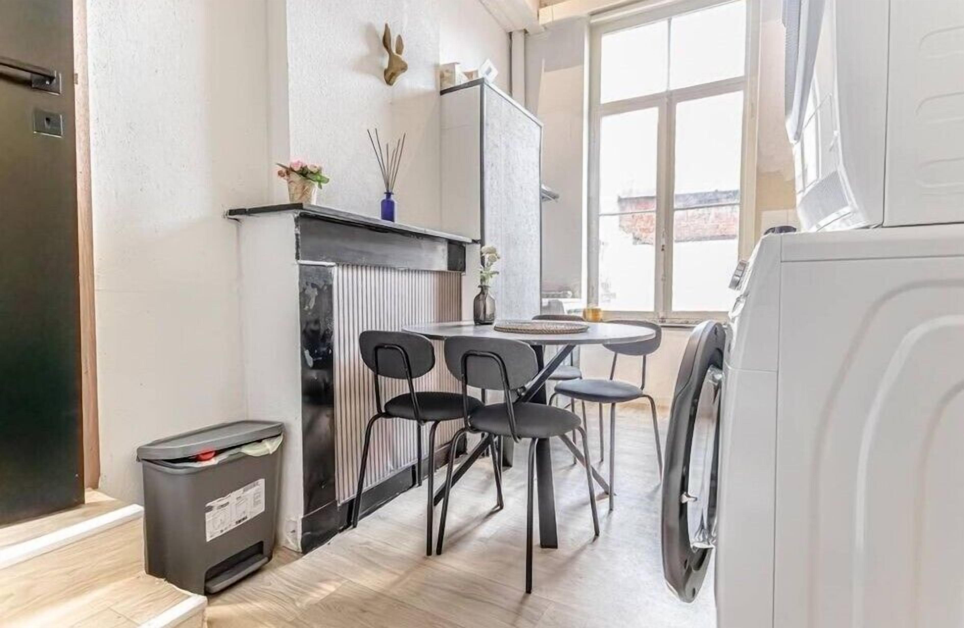 A compact kitchen with a dining area, a radiator, and a washing machine.