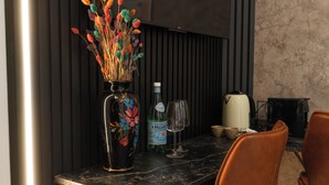 Una mesa de comedor con un jarrón de flores de colores, una botella de agua S.Pellegrino y una copa de vino.
