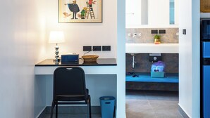 A modern kitchen with a countertop, a chair, a trash bin, and a framed picture on the wall.