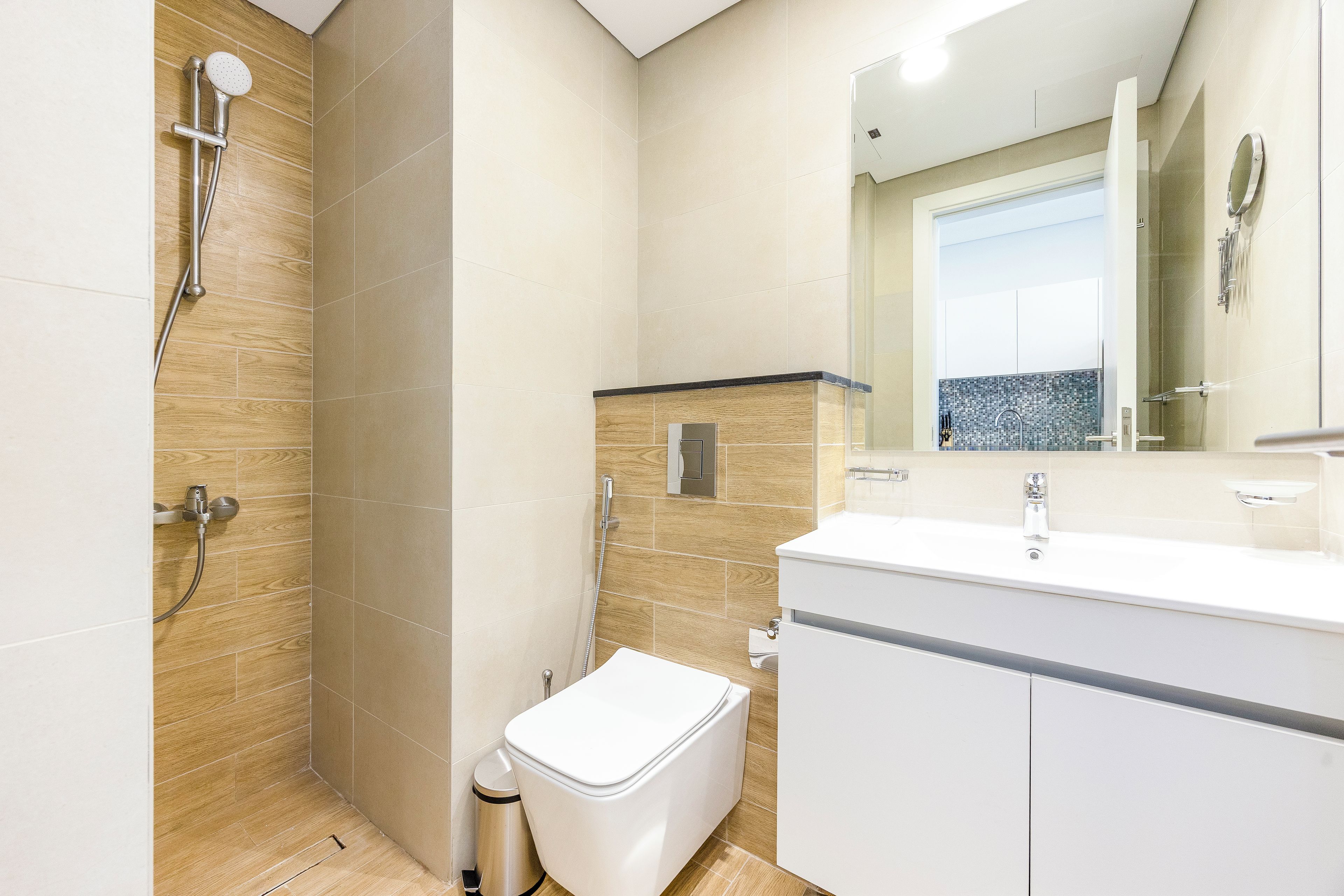 Een moderne badkamer met douche, toilet en wastafel.
