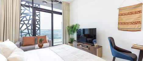 A hotel room with a large bed, a TV, a desk, and a chair.