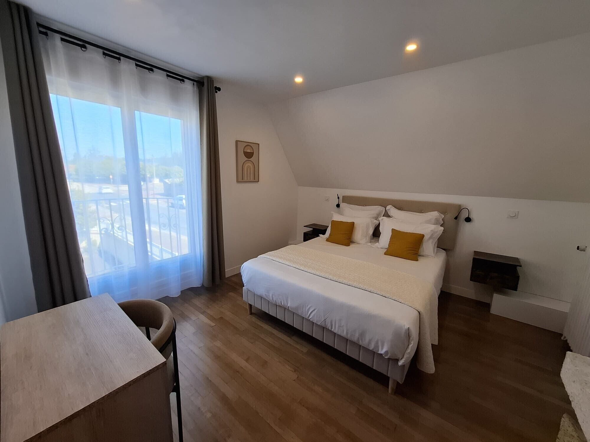 A hotel room with a large bed, a desk, and a view of the outdoors.