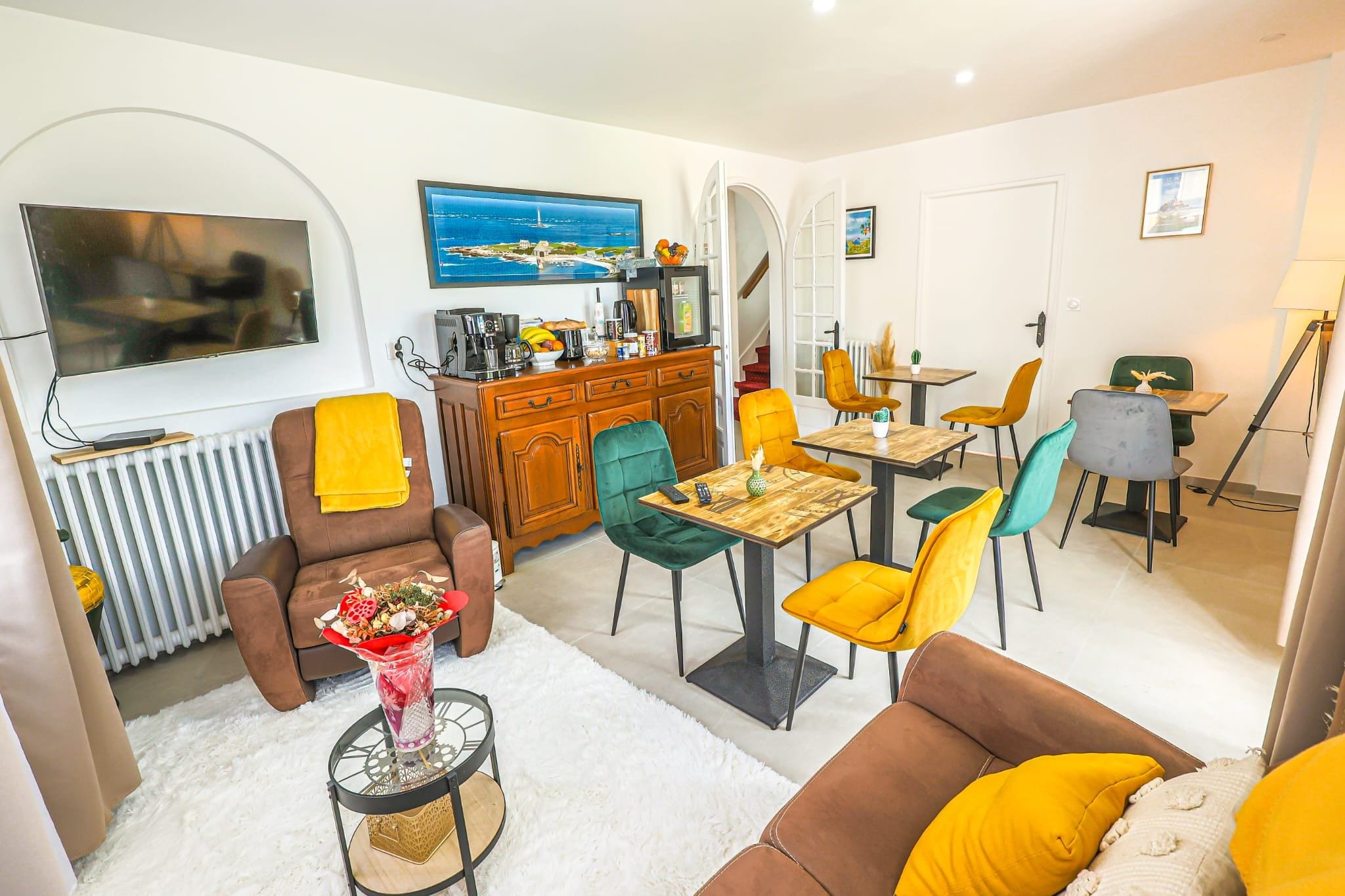A modern living room with a sofa, armchairs, a coffee table, and a dining area with chairs and a table.
