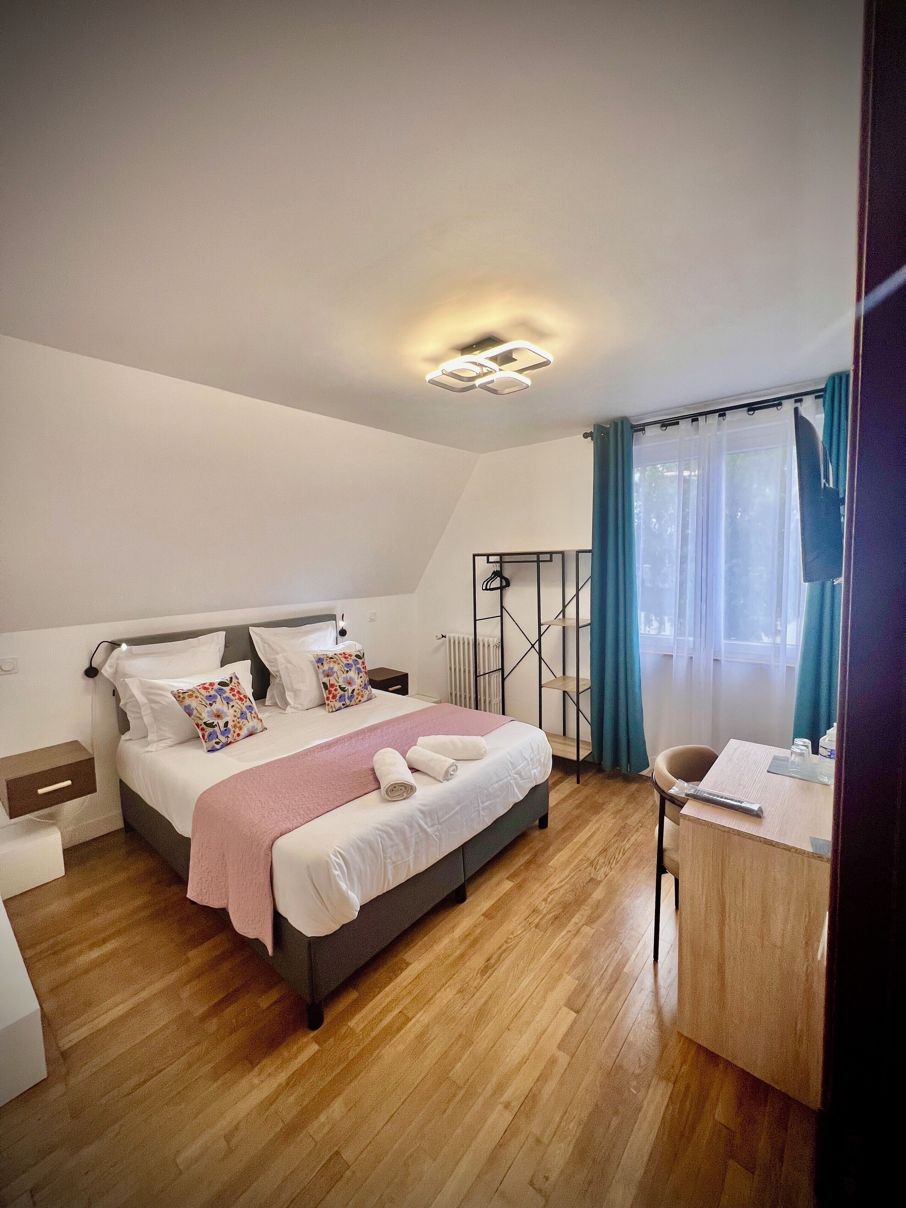 A modern bedroom with a bed, bedside tables, a desk, and a chair.