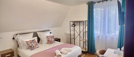 A modern bedroom with a bed, bedside tables, a desk, and a chair.